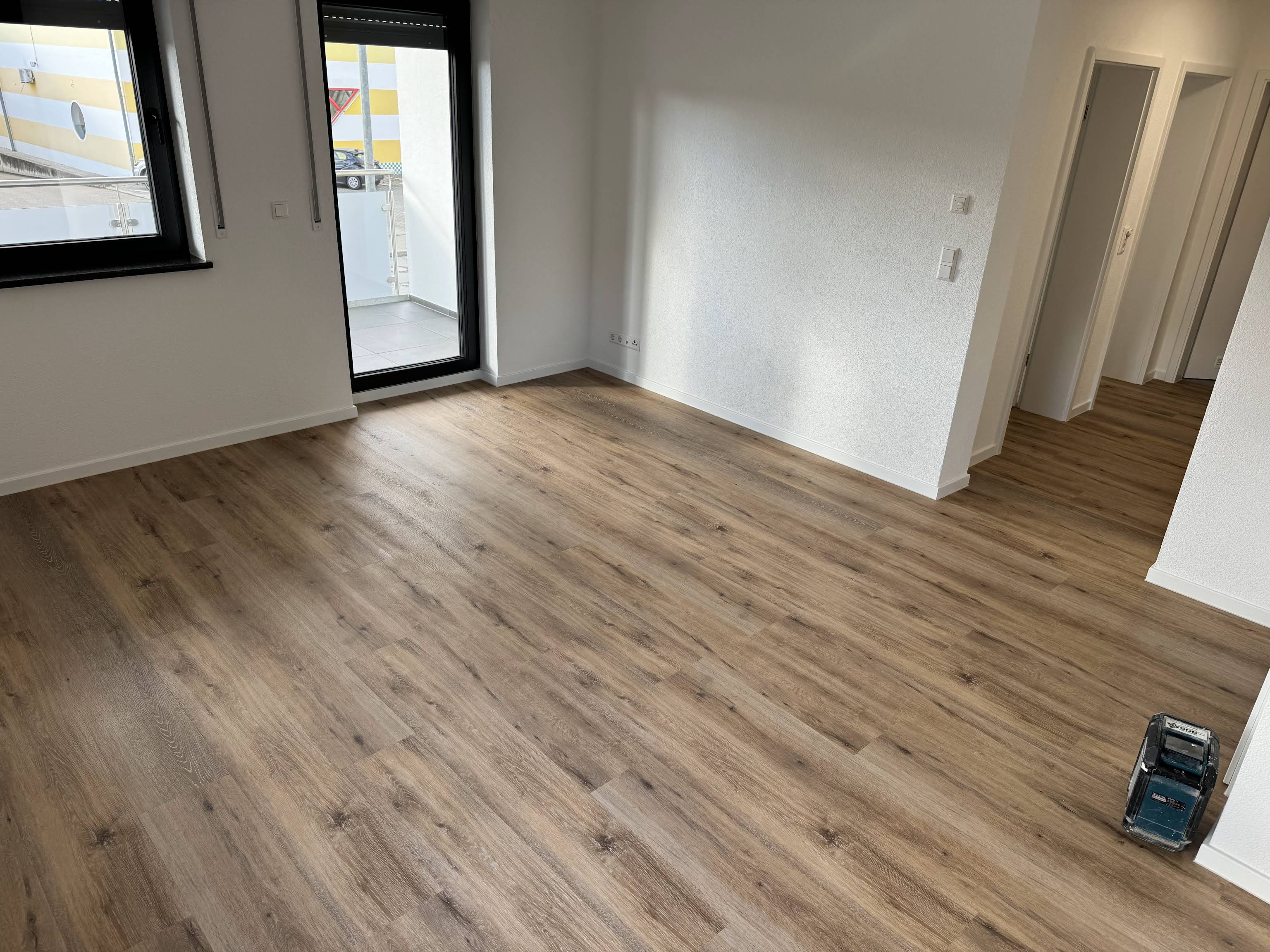 Wohnraum mit Vinylboden in Holzoptik und Zugang zum Balkon, verlegt von Fliesen & Vinyl BOGAJ